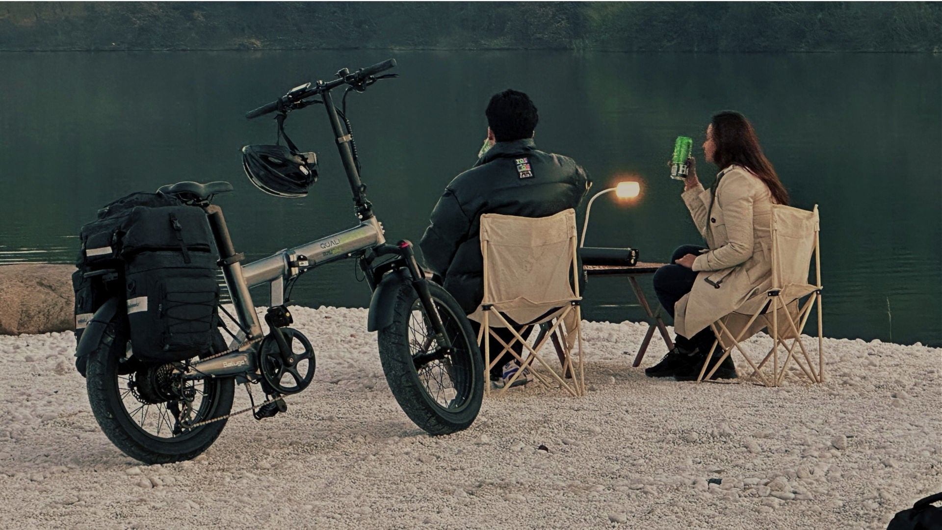 Two people sitting in chairs by a lake with a qualisports beluga plus electric bicycle nearby