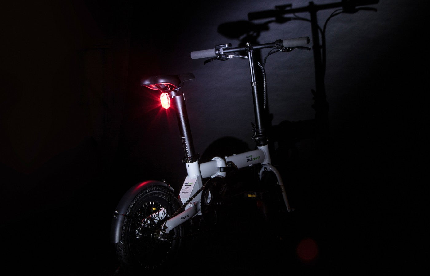 qualisports nemo folding ebike with red tail lights on in the dark