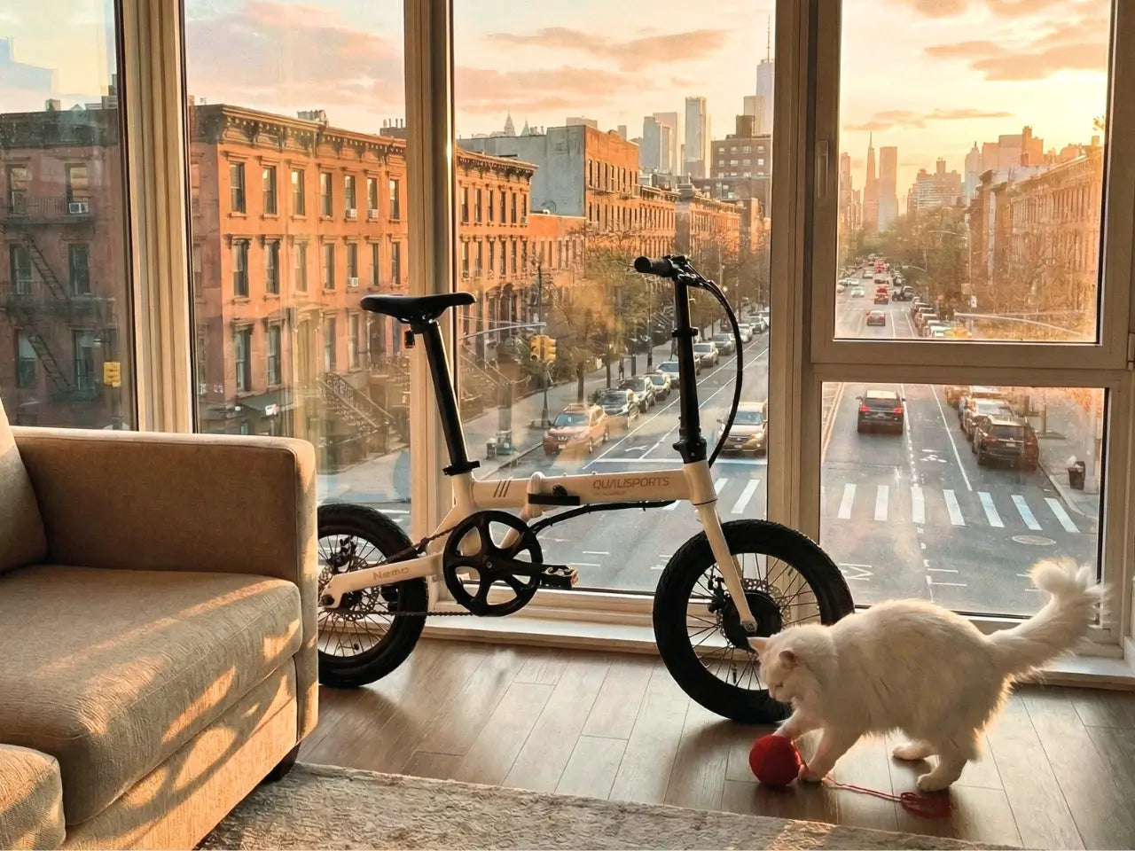 lightweight electric bicycle next to a cat playing with a ball in a room with large windows showing a cityscape.