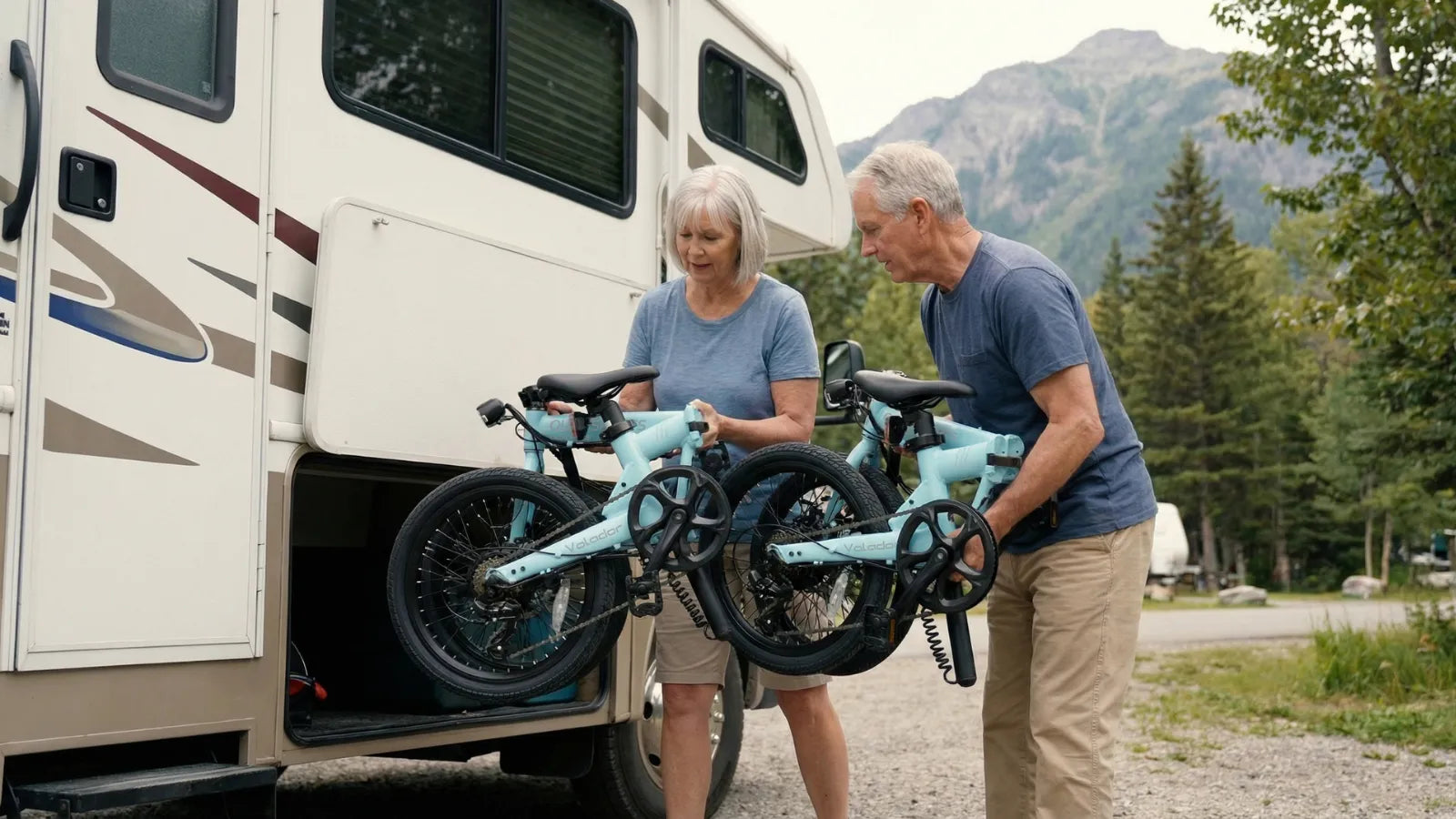 Man and woman unloading volador bicycles from an RV in a scenic outdoor setting.